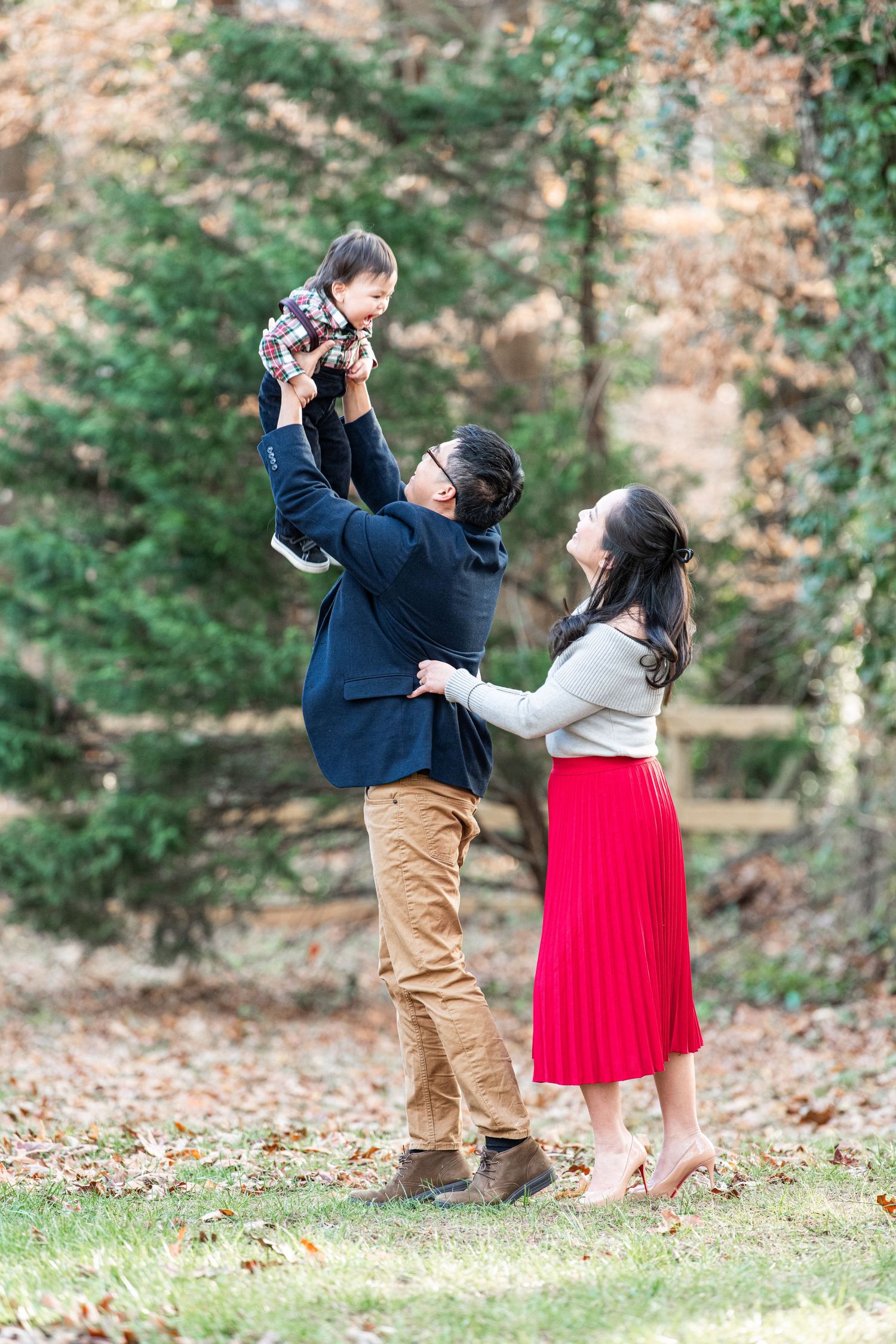 Lovely young parents holding their happy, sweet baby for the holidays, set against a beautiful, natural background.