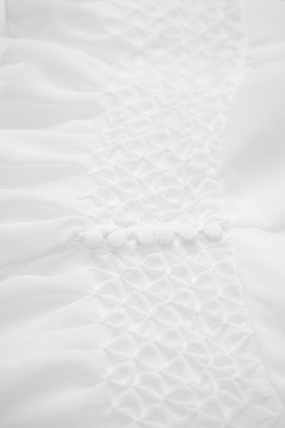 Close-up detail of intricate white lace pattern on wedding dress fabric.