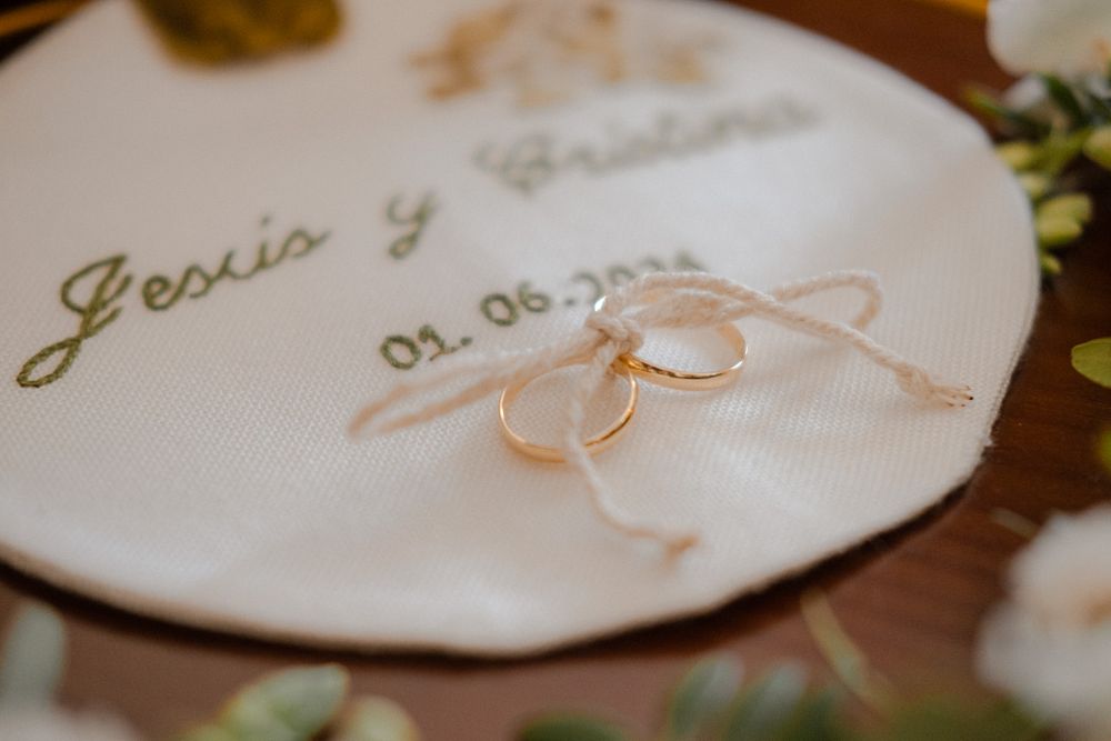 Wedding rings displayed on personalized plate with names and date.