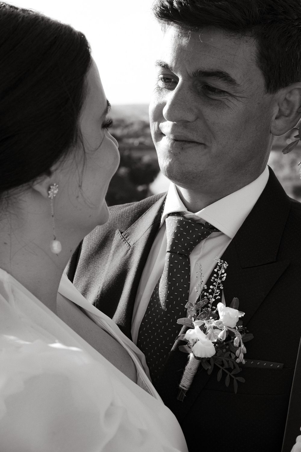Intimate black and white portrait of newlyweds sharing a romantic moment outdoors.
