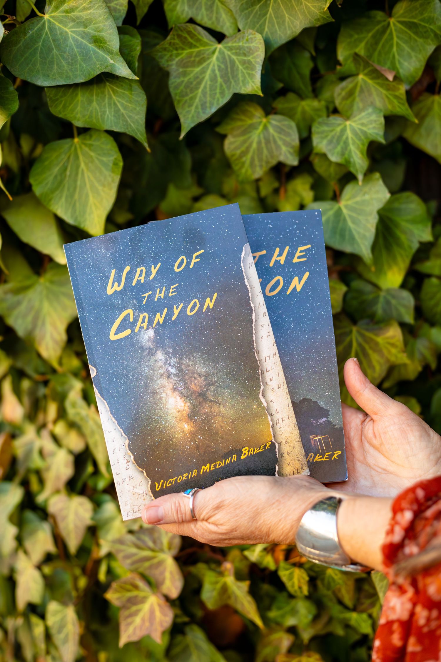 Book cover titled 'The Way of the Canyon' held against lush green ivy background.