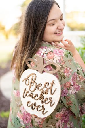 Decorative 'Best Teacher Ever' sign displayed against a floral patterned fabric background.