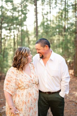 Romantic forest portrait of a couple sharing a tender moment among pine trees.
