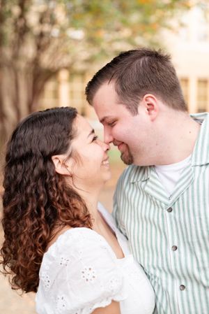 A tender moment captured between a couple in white and striped clothing outdoors.