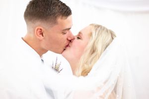 Romantic wedding portrait of couple sharing kiss under veil.