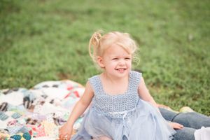 Playful outdoor scene on a patchwork quilt blanket in soft natural lighting.
