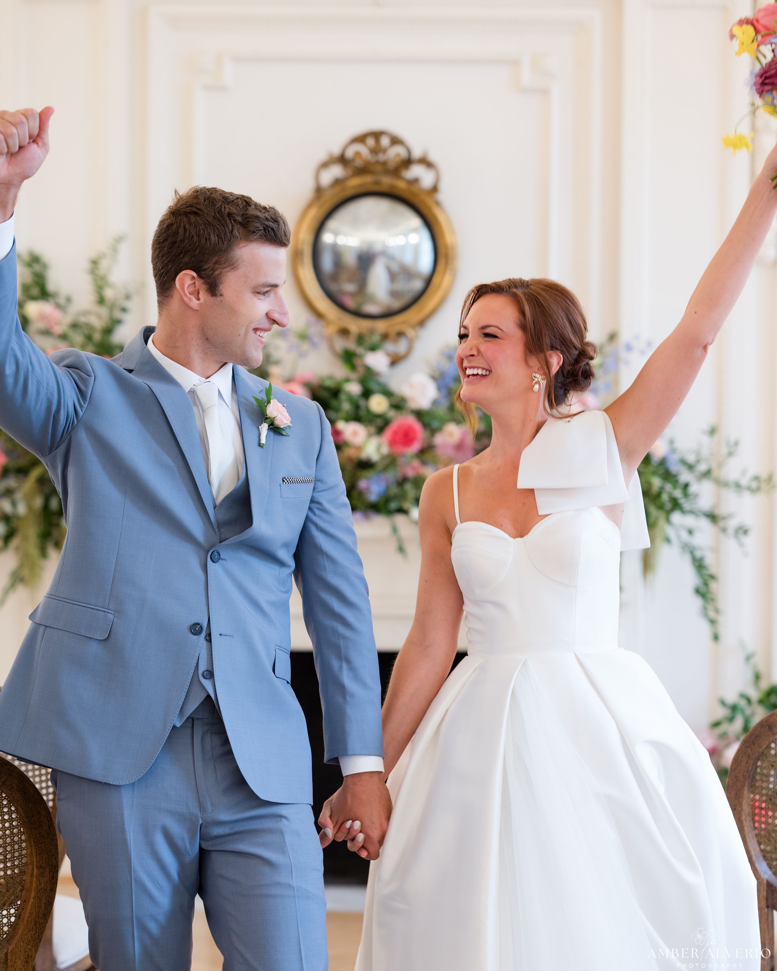 Joyful wedding celebration moment with couple in light blue suit and white gown.