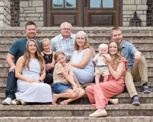Multi-generational family portrait on stone steps of historic building.