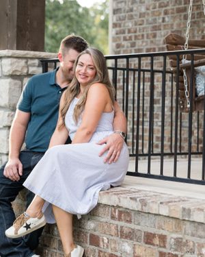 Casual couple sharing tender moment while sitting on brick porch steps.