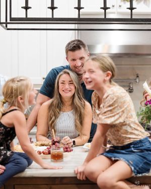 Casual family gathering around kitchen table with drinks and laughter.