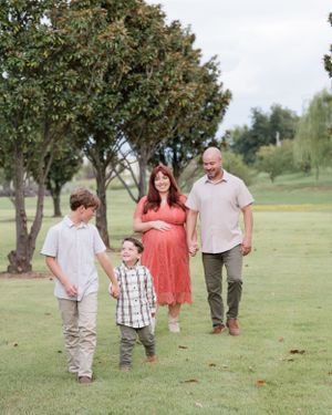 A family walks together on green grass in a park with mature trees in the background on a peaceful afternoon.