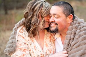 Close-up outdoor portrait of a couple in tender embrace wearing cozy attire.