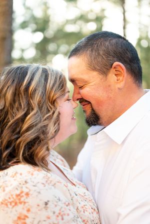 A romantic outdoor portrait of a couple sharing an intimate moment in a sunlit forest setting.