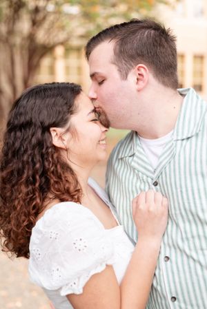 A romantic outdoor portrait of a couple sharing an intimate moment near a stone building.