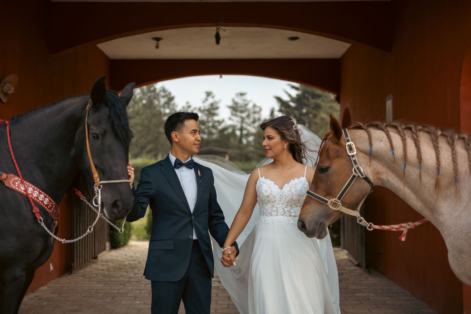 Couple poses with a horse in a rustic barn setting during their wedding day.