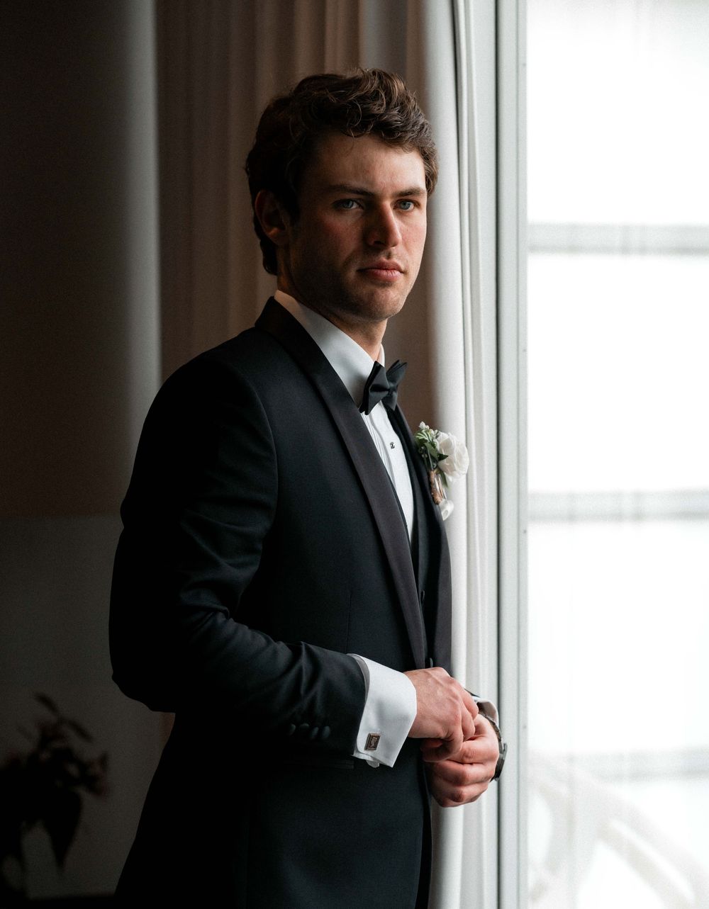 A series of silhouetted formal portraits showing a person in a dark suit adjusting their attire against a bright window.