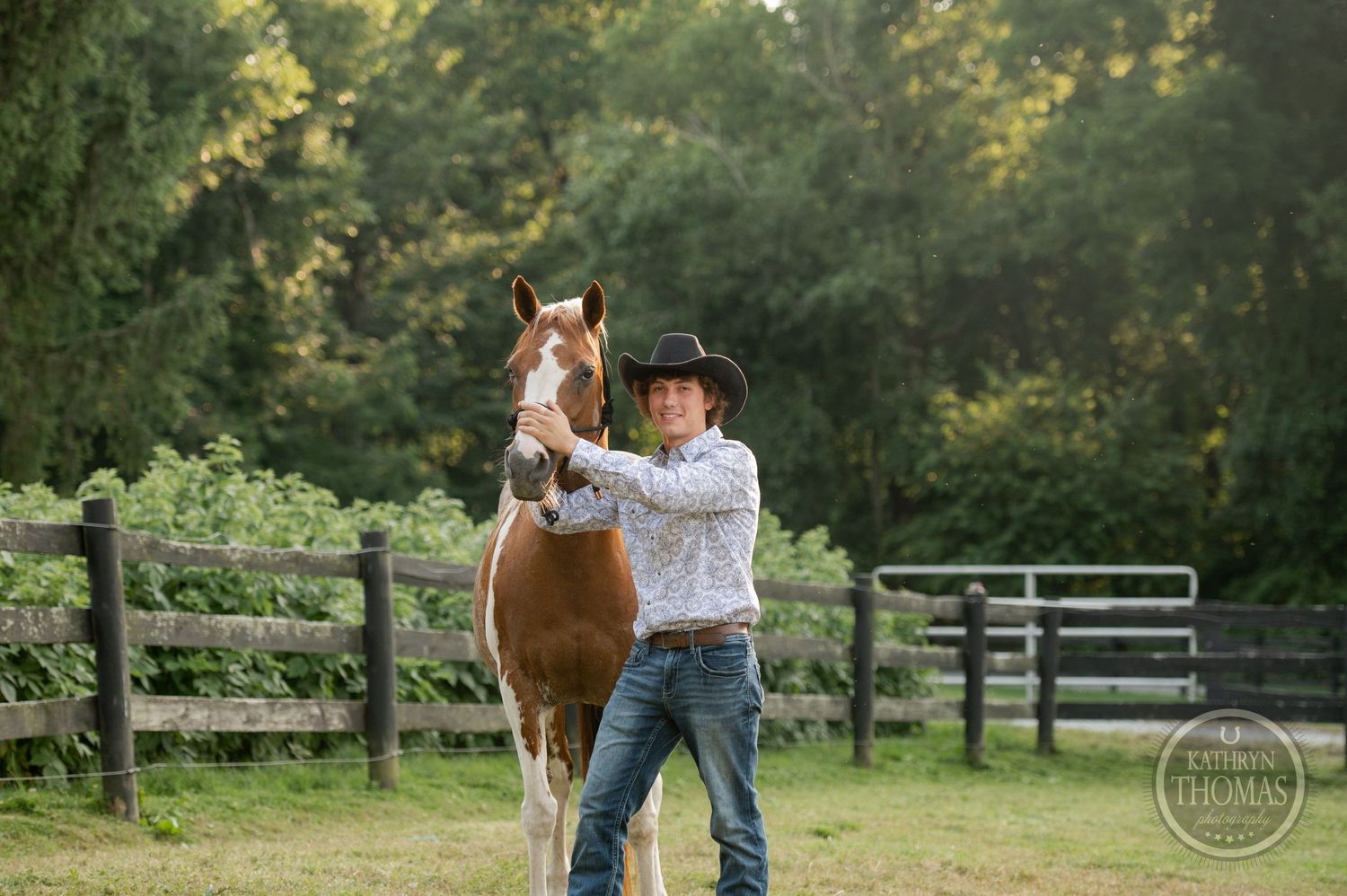 Paint horse and handler posing together in front of a rustic wooden fence at sunset.