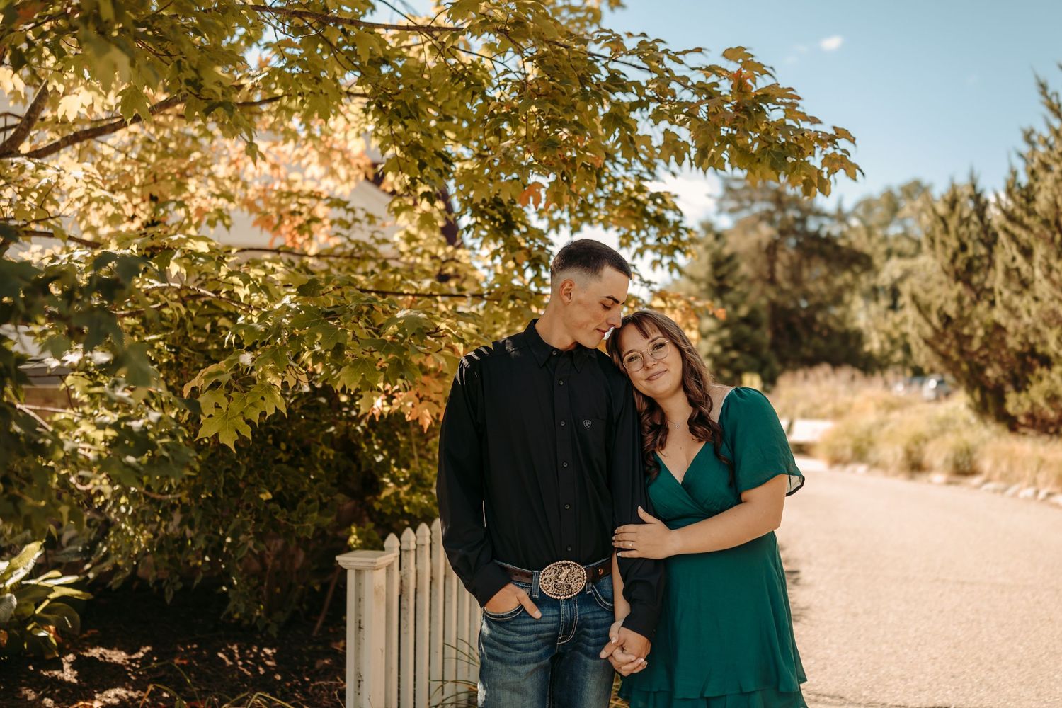 A romantic couple embraces in a wildflower field beside a rustic wooden barn on an autumn afternoon.