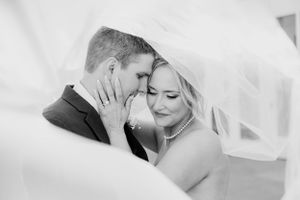 A tender romantic moment captured in black and white between a couple under a flowing bridal veil.
