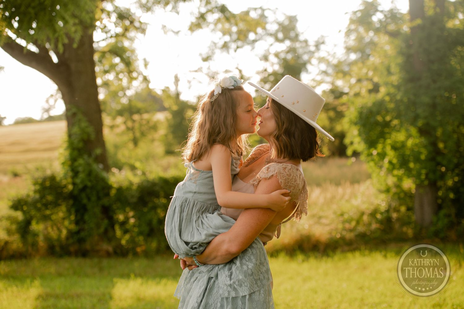Joyful embrace captured in golden hour lighting against a pastoral countryside backdrop.