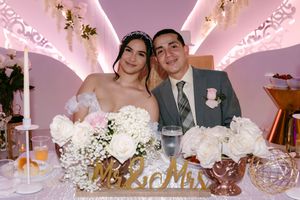 Bride and groom smiling at wedding reception sweetheart table with white roses and Mr & Mrs sign.