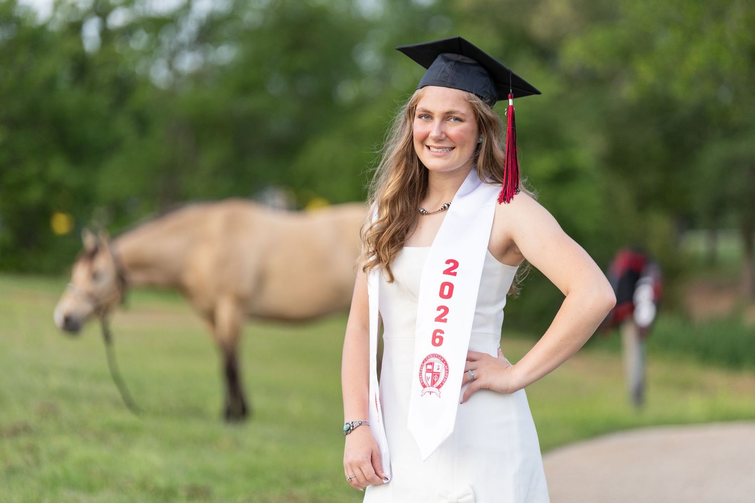 graduation picture focused on the grad with her horse in the background