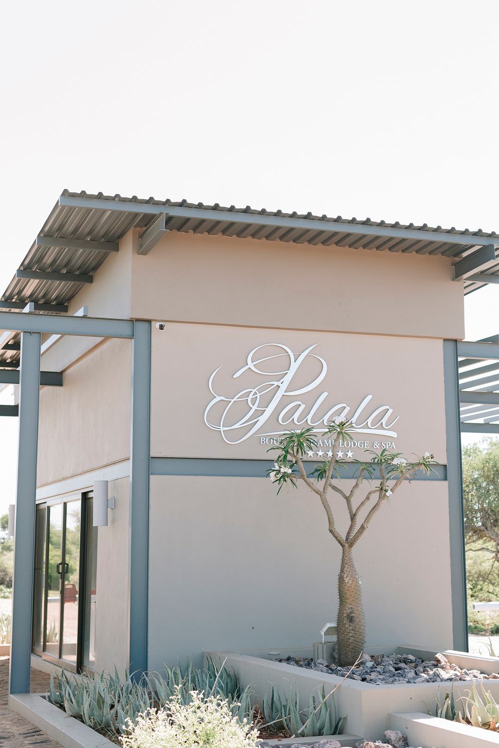 Elegant Palola wedding venue entrance sign with succulent garden and contemporary architectural details outdoors. Palala Boutique Game Lodge