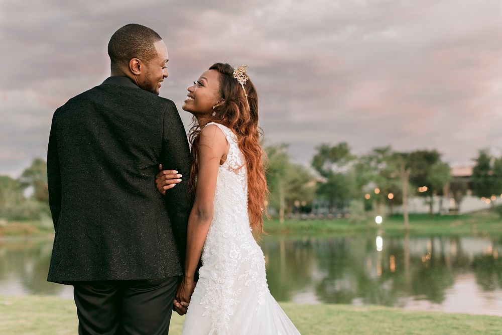 African American wedding couple gazing at each other romantically by a scenic lake at sunset. Palala Boutique Game Lodge & Spa.