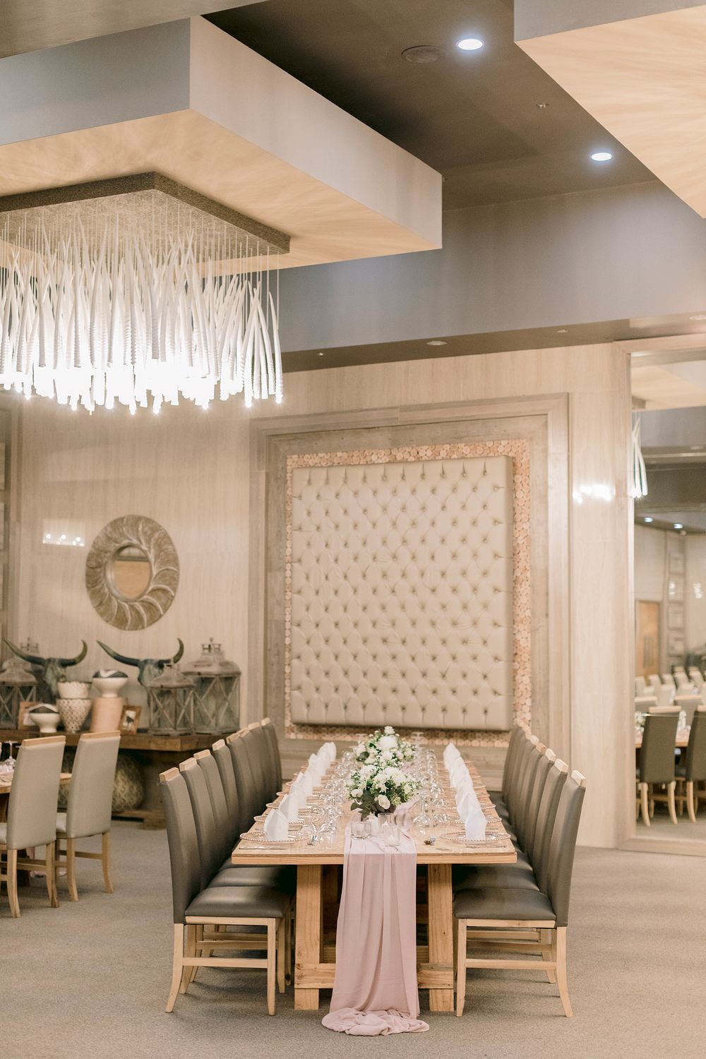 Glamorous reception hall featuring a fringe chandelier, tufted headboard wall, and elegantly set wooden table. Palala Boutique Game Lodge &