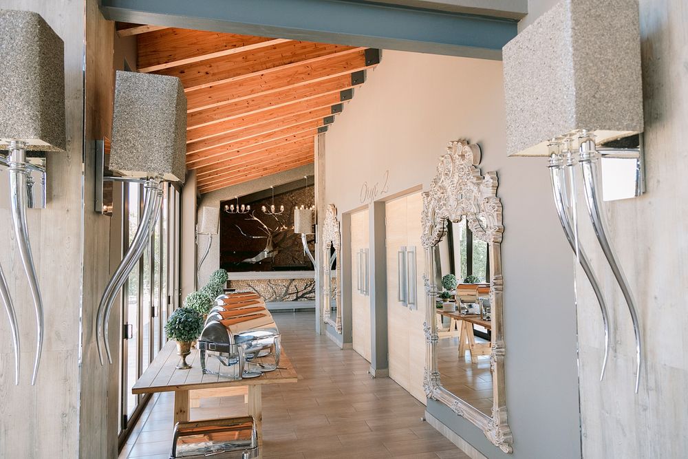 Sophisticated venue interior hallway with wooden ceiling, ornate silver mirror, and decorative wall sconces. Palala Boutique Game Lodge & Sp