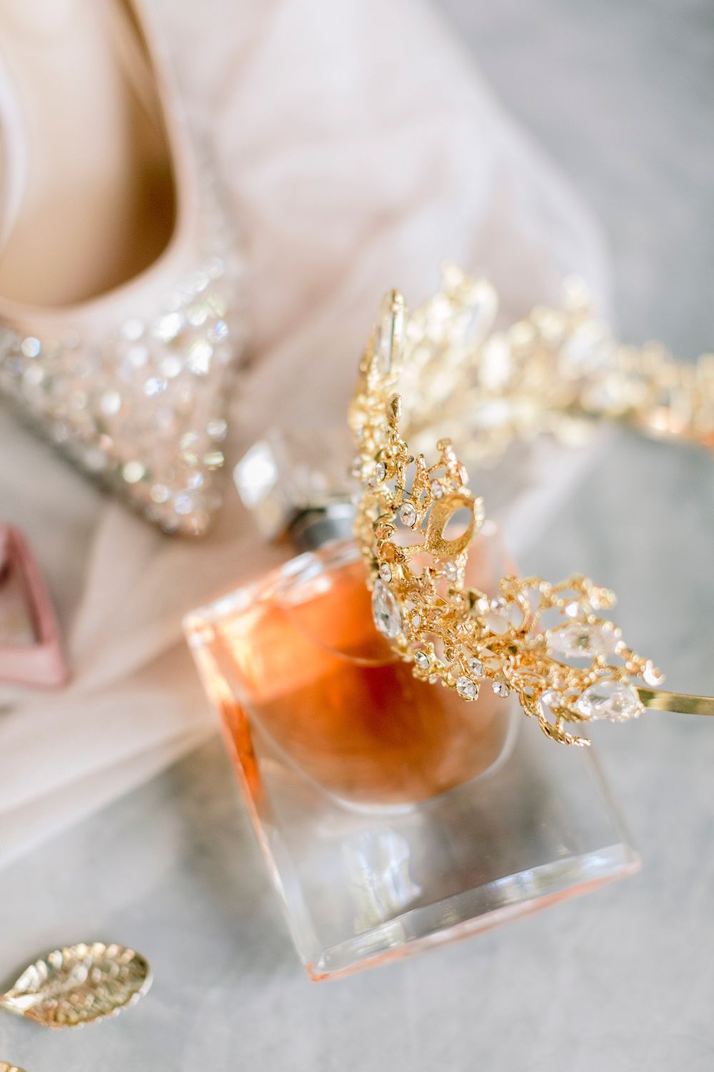 Gold bridal crown resting on a perfume bottle beside crystal-embellished wedding heels and accessories. Palala Boutique Game Lodge & Spa.