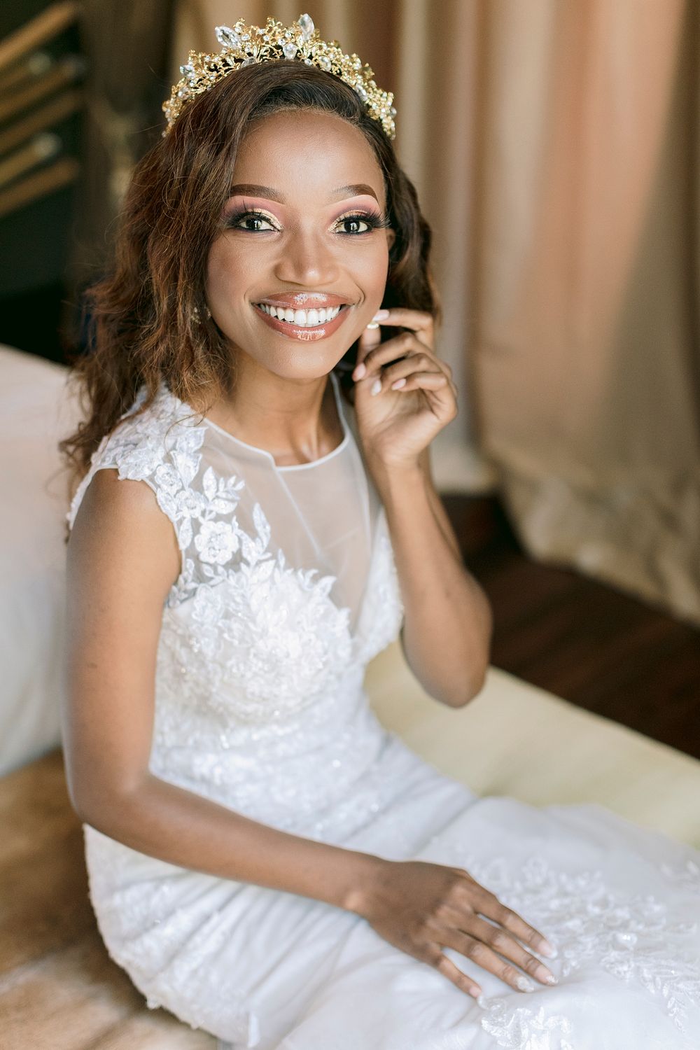 Joyful Black bride in white lace gown and gold crown smiles brightly while seated. Palala Boutique Game Lodge & Spa.