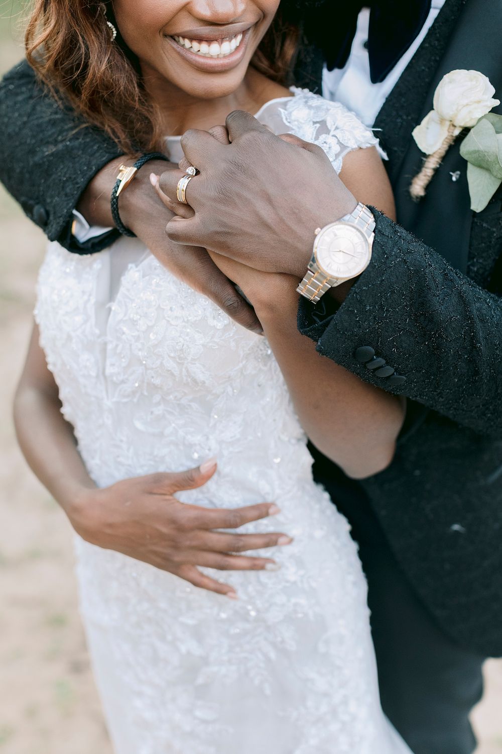 Close-up of groom embracing bride in beaded lace gown, showing wedding rings and gold watch. Palala Boutique Game Lodge & Spa.