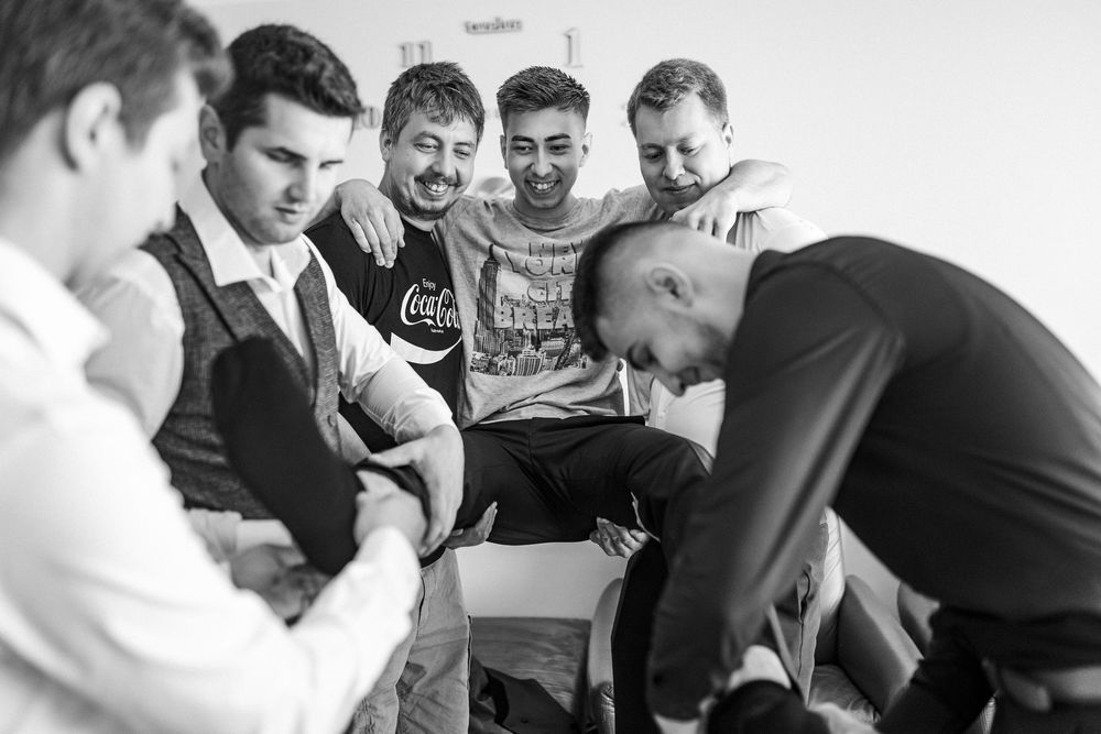 Black and white photo of groom and groomsmen laughing together during wedding preparations.