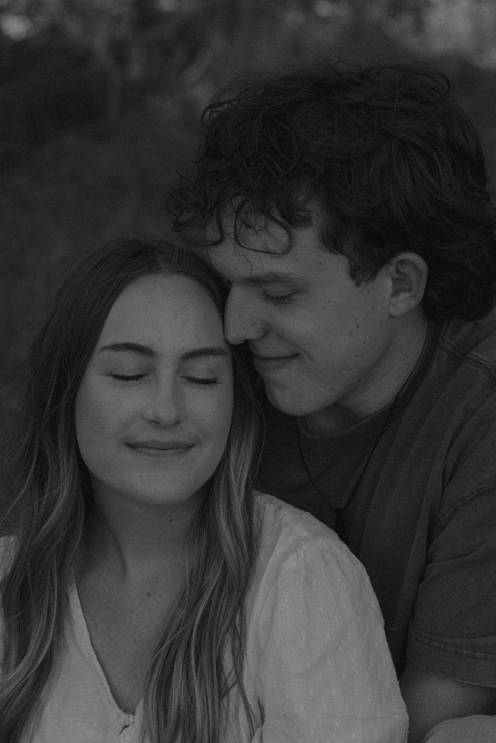 Black and white close-up of couple sharing a tender quiet moment with eyes closed.