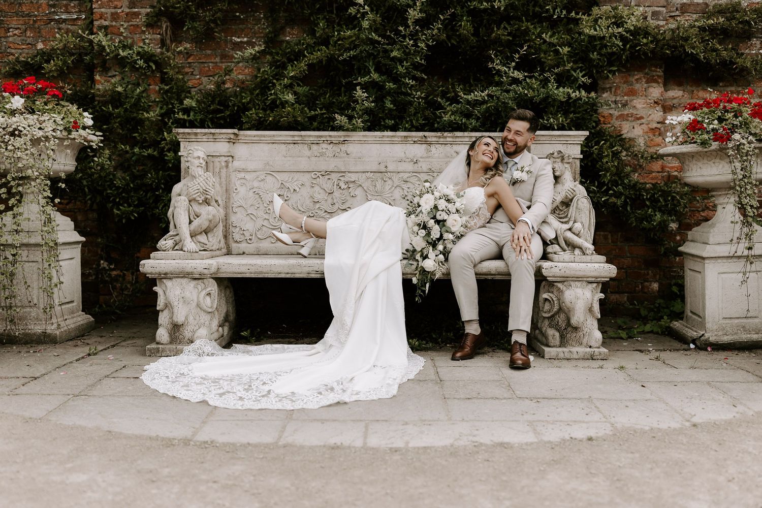 Bride and groom share first dance surrounded by cheering guests in elegant white barn wedding venue with sparkling chandeliers.