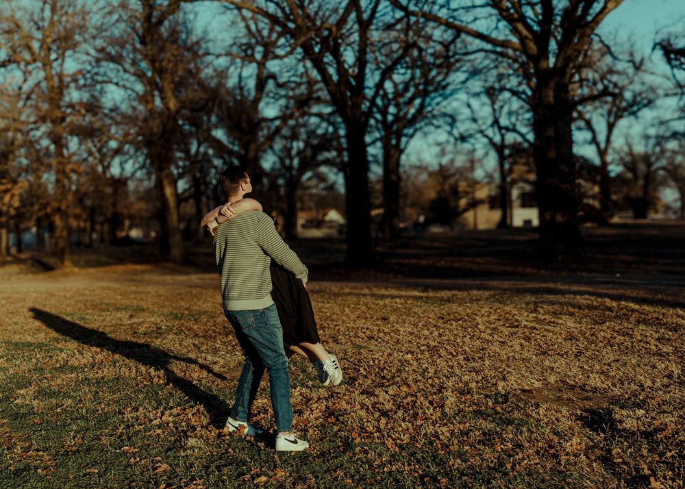 A couple embraces while dancing together on a sunny autumn day in a park.