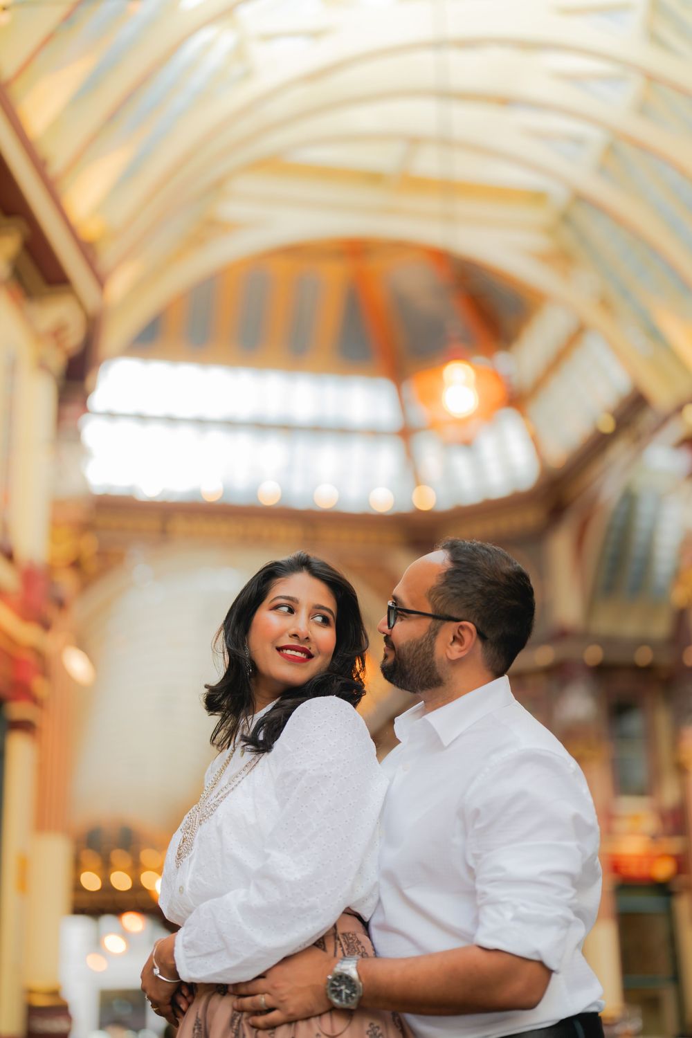 A couple shares a romantic moment under the ornate vaulted ceiling of Leadenhall Market in London.