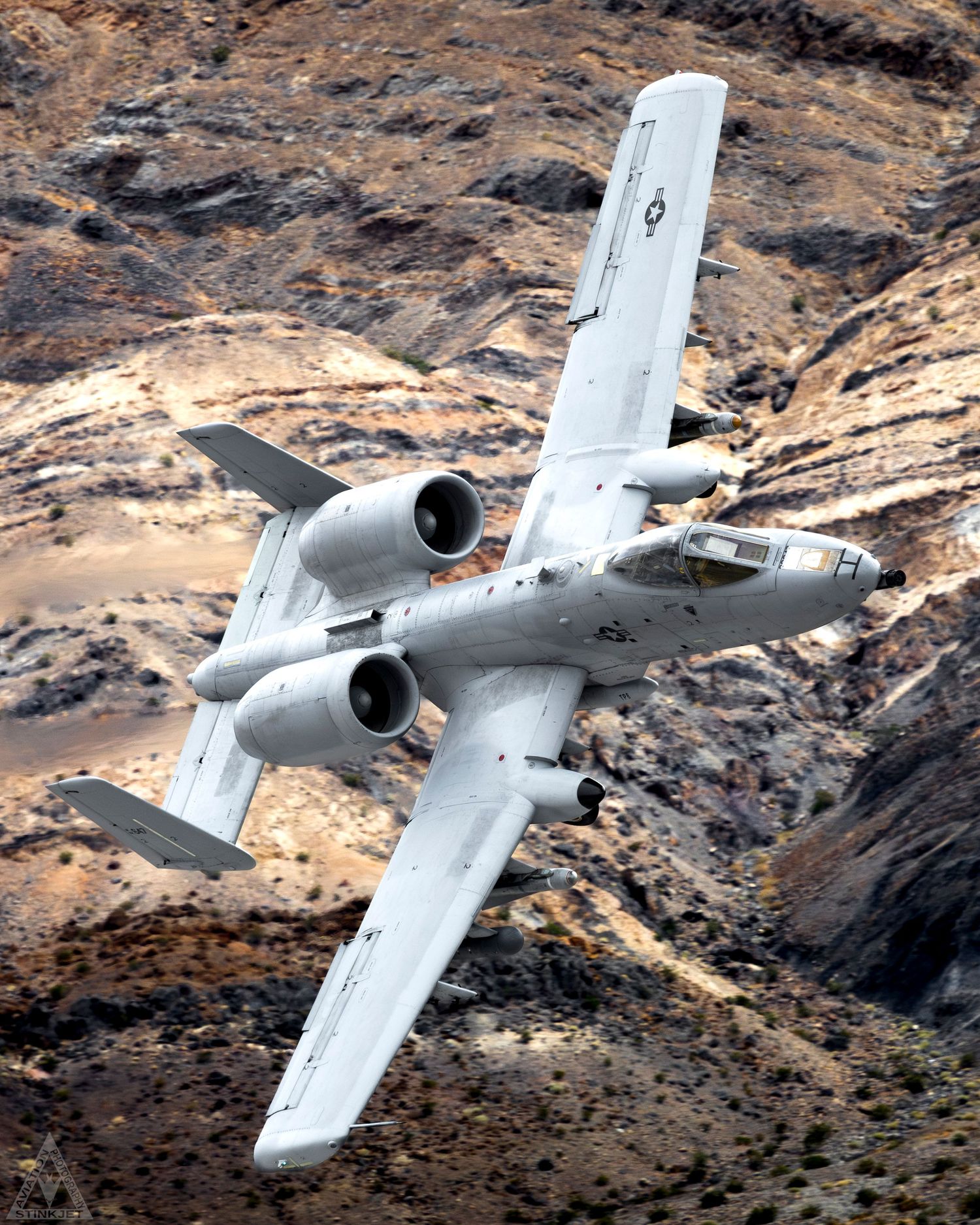 an A-10C soaring with a magnificent layered desert cliffside in the background