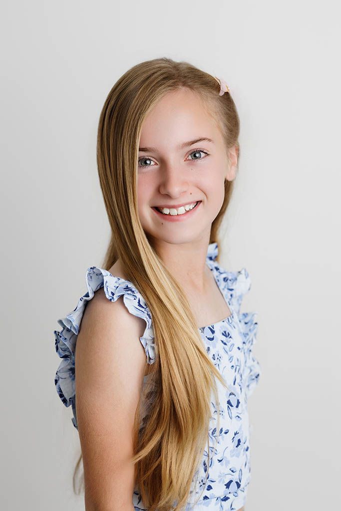 Smiling girl poses against a white backdrop by Canyon Lake Photographer.