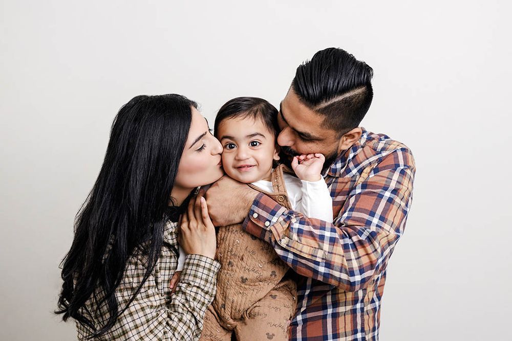 Moreno Valley family and baby photographer photo of parents cuddling their smiling baby during a professional portrait studio session.