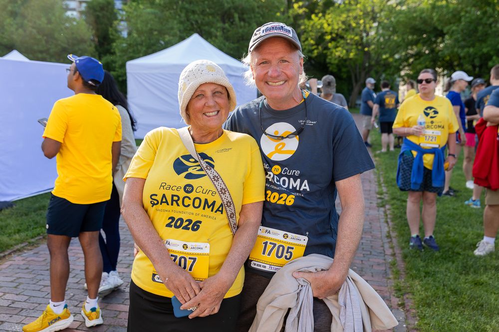 Two smiling participants wearing Sarcoma 2026 race bibs pose together at an outdoor charity run event.