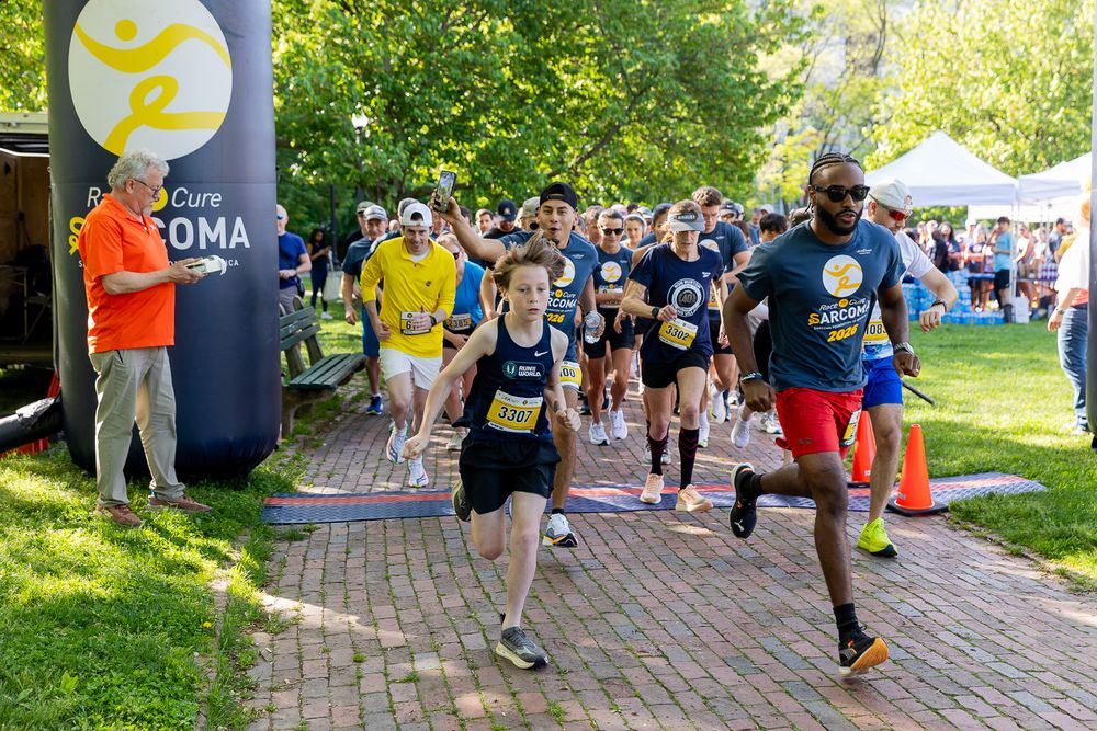Runners start a charity race at the Beat and Cure Sarcoma event on a sunny day in a park setting.