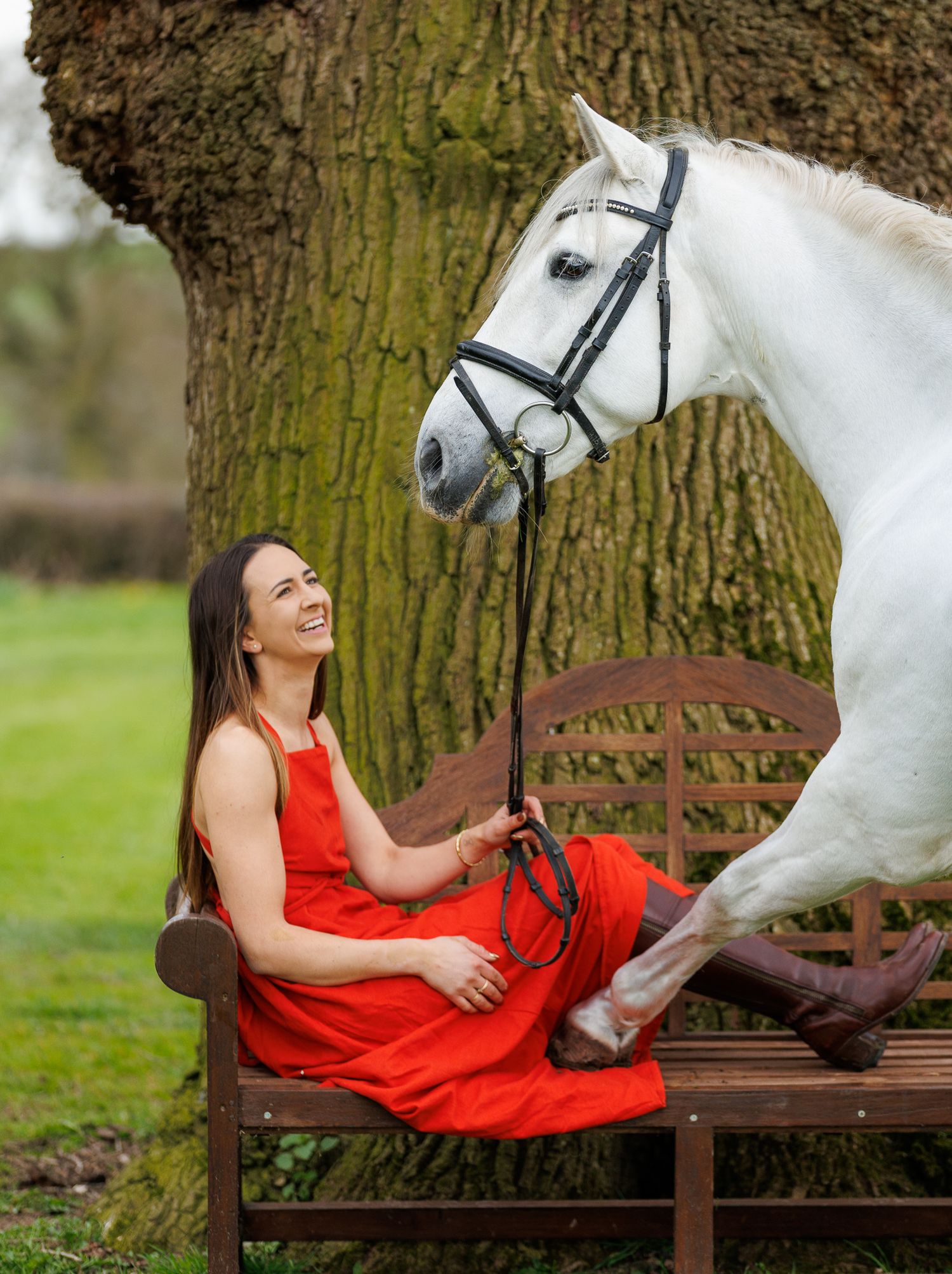 Woman with a paint horse among daffodils by a wooden fence in a lush green countryside setting.
