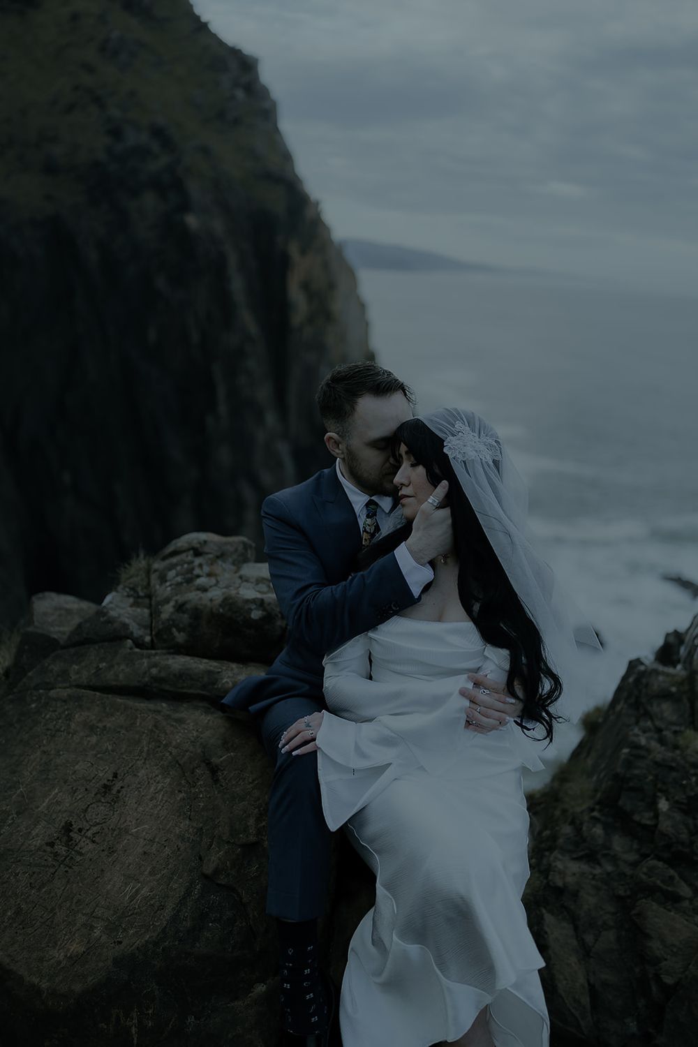 A couple shares a romantic kiss on rocky coastal cliffs at their Elk Flats Trail elopement