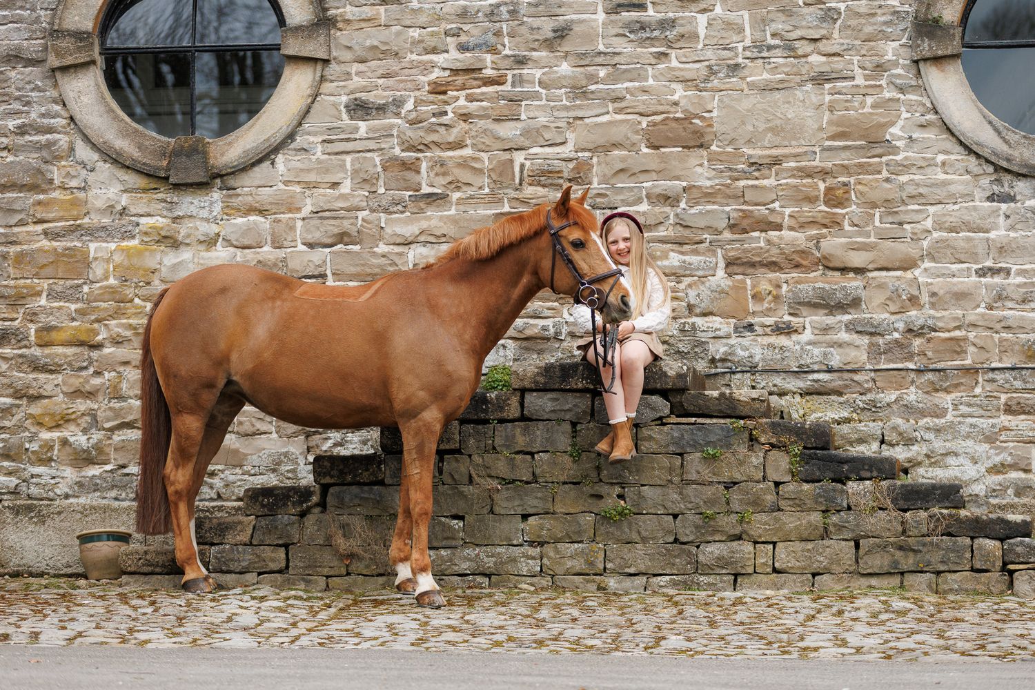 A horse and its rider enjoy an outdoor photoshoot session near rustic wooden fencing on a sunny day.