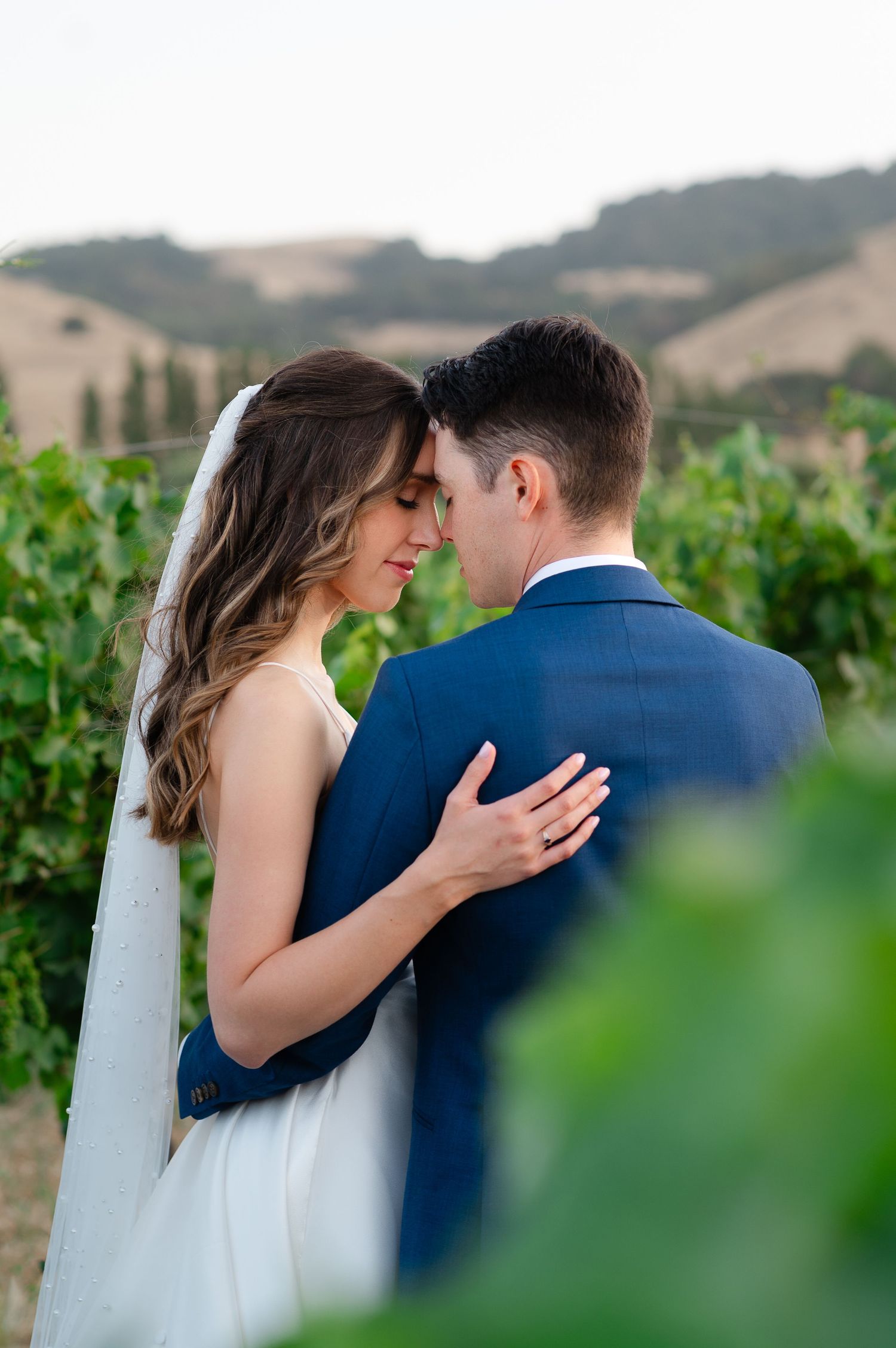 Bride and groom share their first dance in an elegant reception hall with warm string lights glowing through large windows.