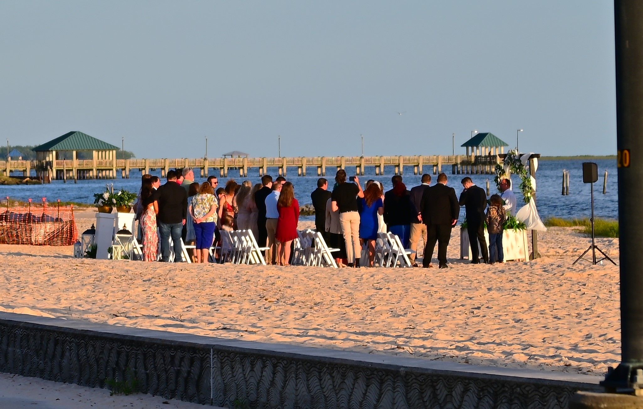 Intimate beach wedding ceremony at golden hour Ocean Springs Mississippi with Gulf Coast pier in background