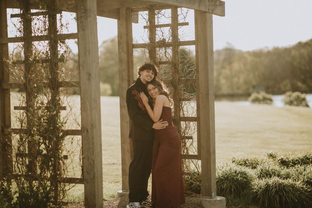 Couple embracing under a wooden pergola in a lush garden, wearing formal attire for a romantic outdoor photo. indiana pa photographer senior