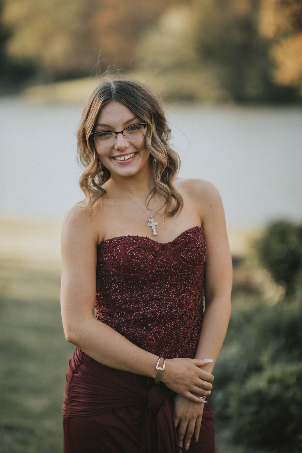 Young woman in elegant strapless burgundy gown posing outdoors near a birdhouse indiana pa photographer, senior in prom dress